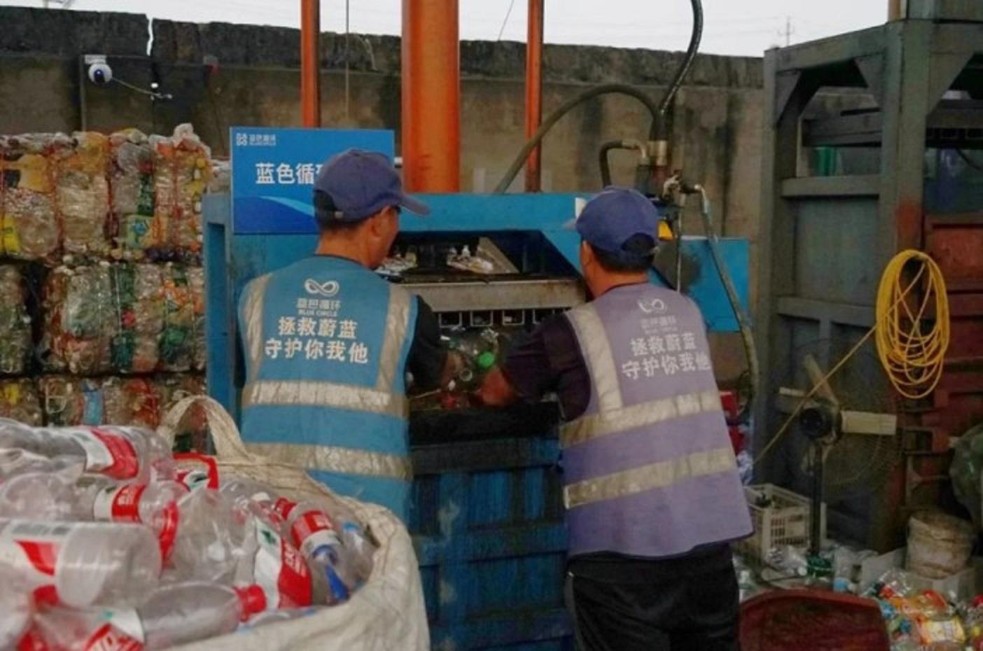 Dua orang pekerja memasukkan botol-botol plastik bekas yang telah disortir ke dalam alat pengompres di "Rumah Biru Kecil" di Distrik Jiaojiang, Kota Taizhou, Provinsi Zhejiang, China, pada 17 Oktober 2023. foto: antara